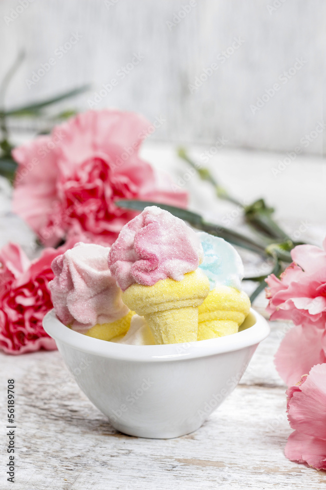 Marshmallows in white bowl among pink carnations