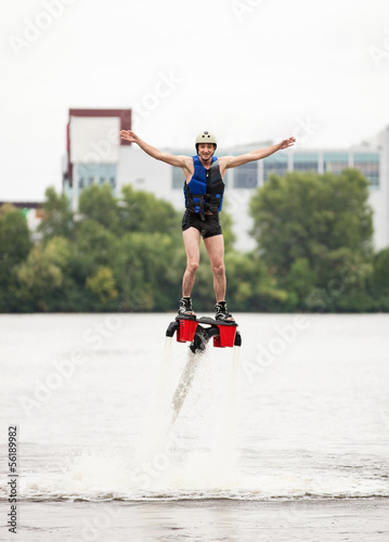 Young man using flyboard machine on river