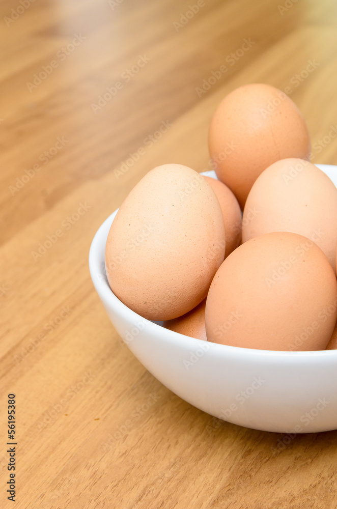 Eggs in white bowl on wooden table Eggs in white bowl on wooden table