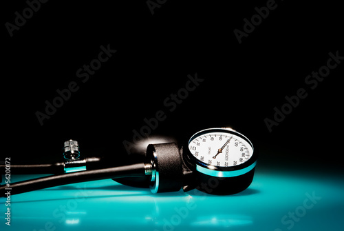 Sphygmomanometer on blue, reflective table and black background