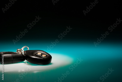 Car keys on blue, reflective table and black background photo