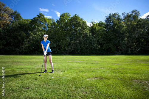 Pretty girl playing golf on grass