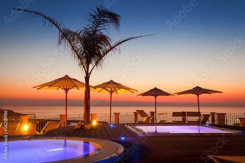 Summer time: beautiful view of red dawn at pool area with palm a