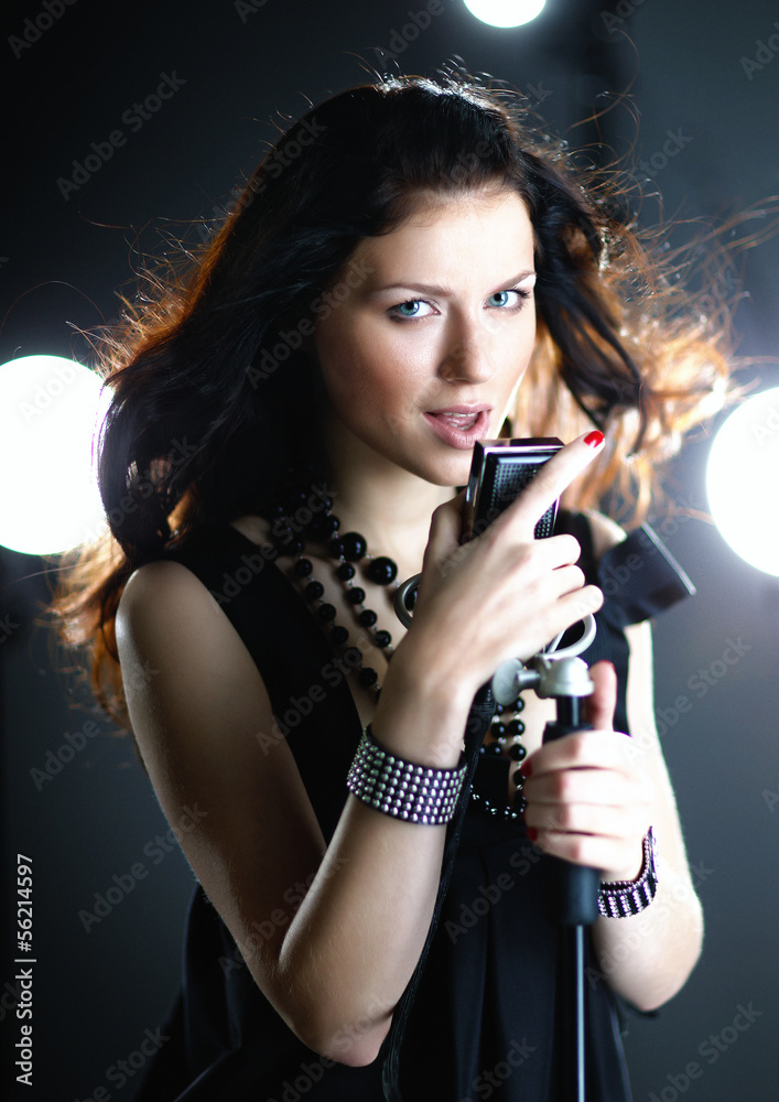 Young woman singing with microphone with back light and flying h Young woman singing with microphone with back light and flying h