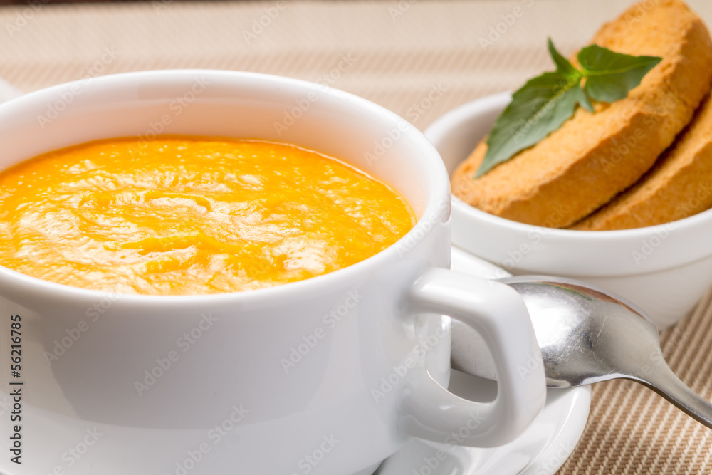 Pumpkin soup in white bowl with fresh basil Pumpkin soup in white bowl with fresh basil