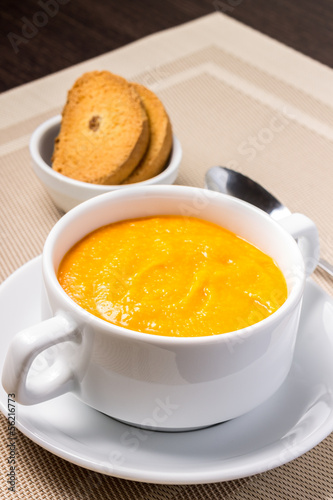 Pumpkin soup in white bowl with crouton