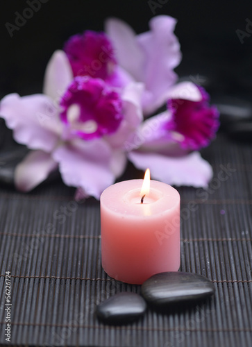 beautiful orchid with candle and zen stones on mat