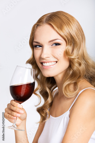 Woman with glass of redwine, on gray