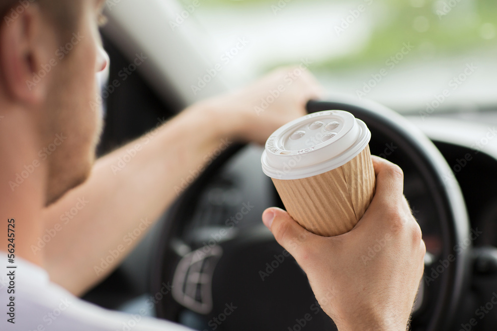 man drinking coffee while driving the car