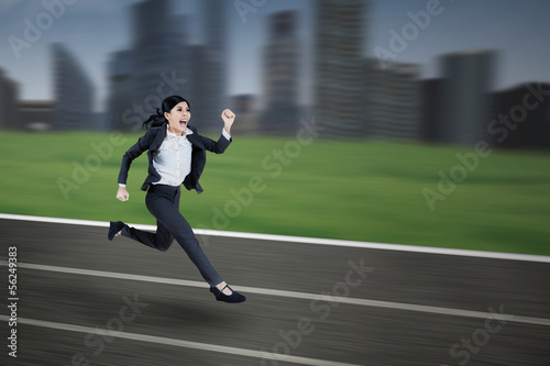 Businesswoman runs on a running track © Creativa Images
