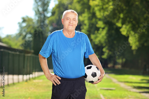 Mature man in sportswear holding a ball in a park © Ljupco Smokovski