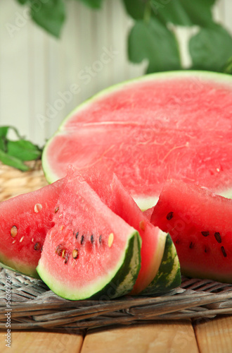 Ripe watermelons on wicker tray on table on wooden background