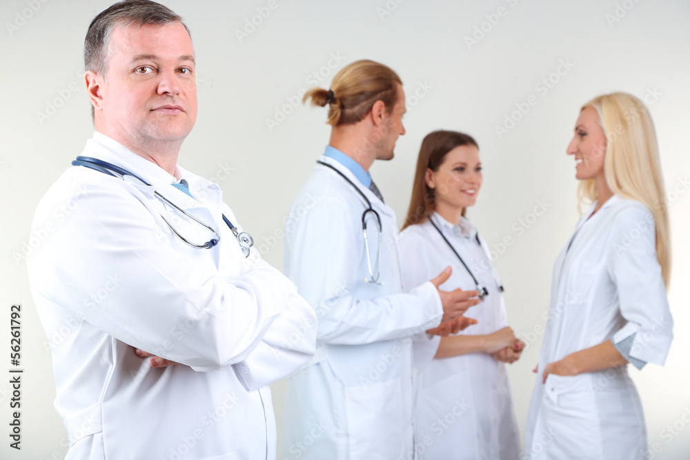Doctor standing in front of coworkers on grey background Doctor standing in front of coworkers on grey background
