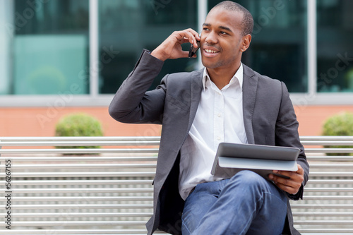 Foto Afro American manager sitting on the bench and phoning