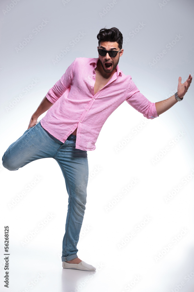 Naklejka premium young fashion man balancing with one leg in his hand