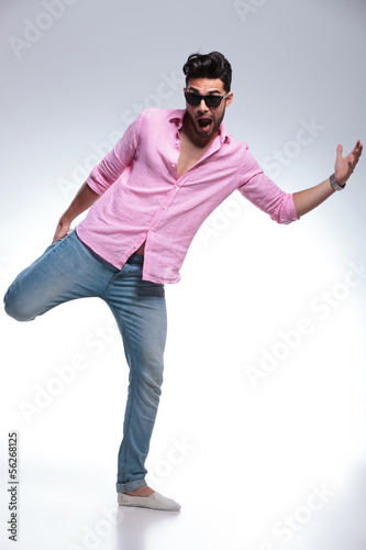 young fashion man balancing with one leg in his hand