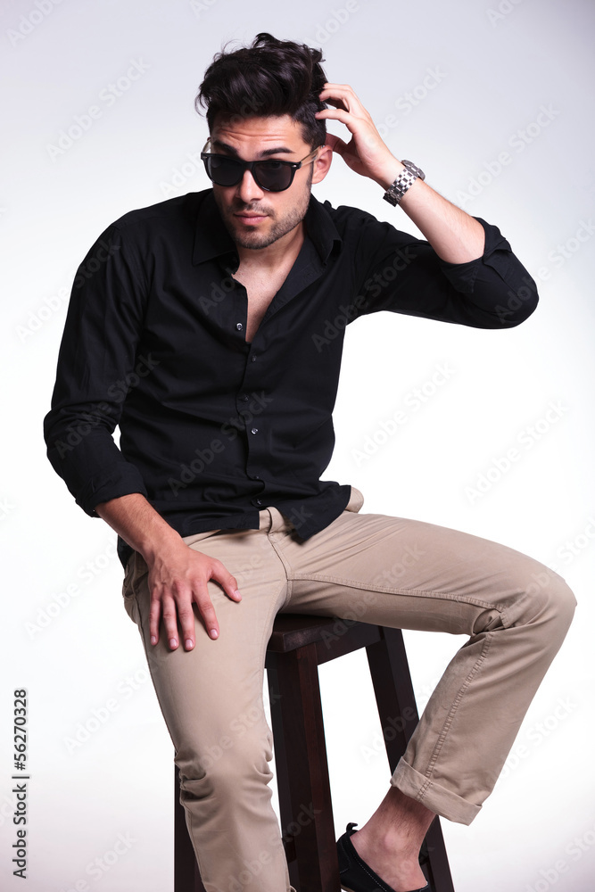 seated young man scratching his head seated young man scratching his head