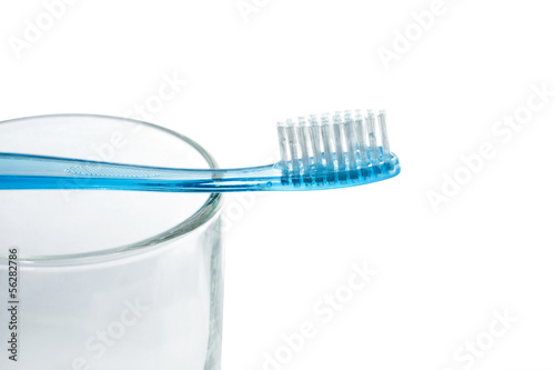 Blue tooth brush lies on a glass on white