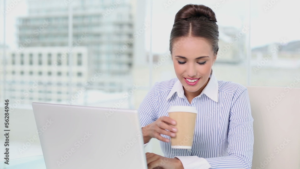 Young businesswoman working on her laptop drinking coffee Young businesswoman working on her laptop drinking coffee