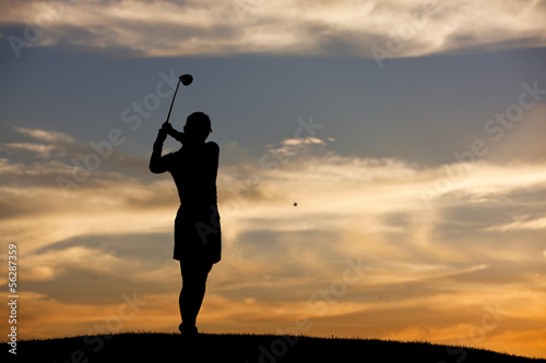Hitting golf ball at sunset.