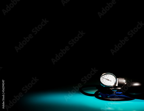 Sphygmomanometer on blue, reflective table and black background