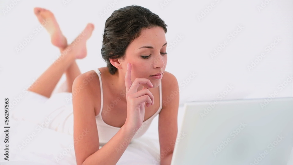 Thoughtful brunette using her laptop and smiling Thoughtful brunette using her laptop and smiling