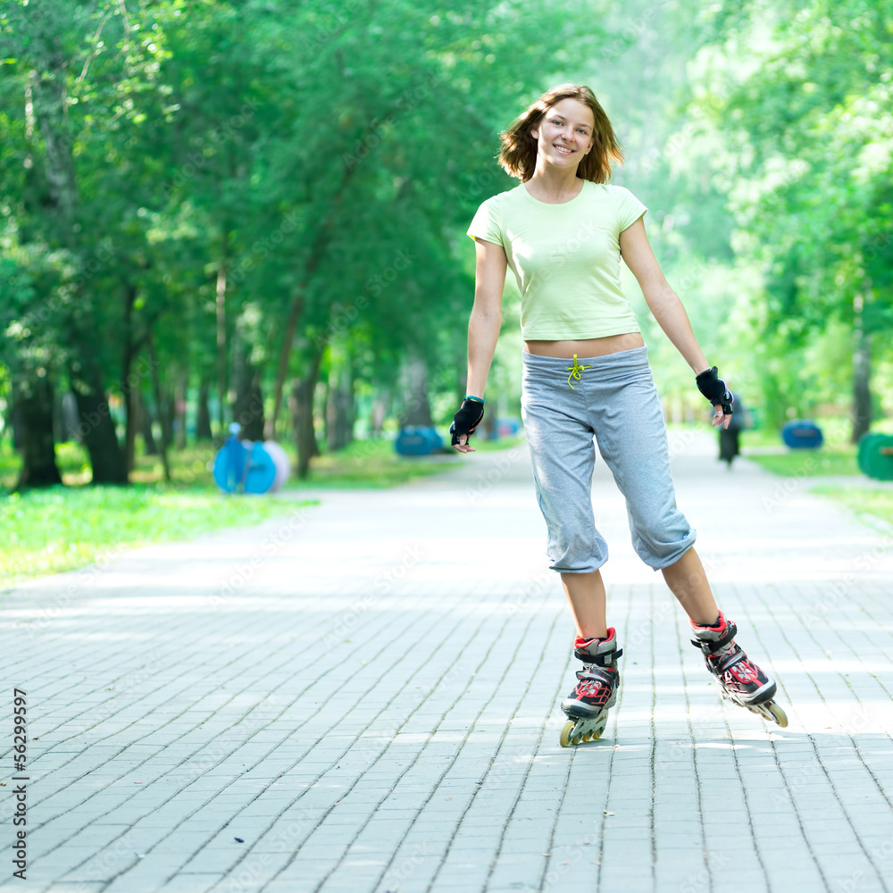 Fototapeta premium Roller skating sporty girl in park rollerblading on inline skate