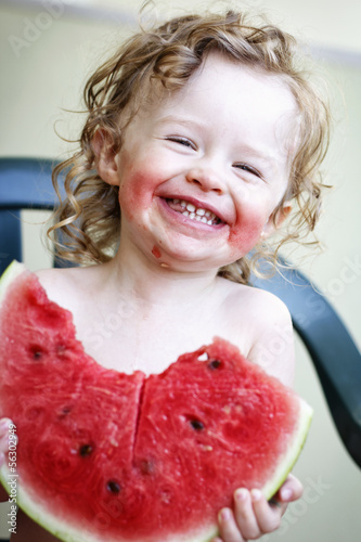 Little girl laughing and eating melon