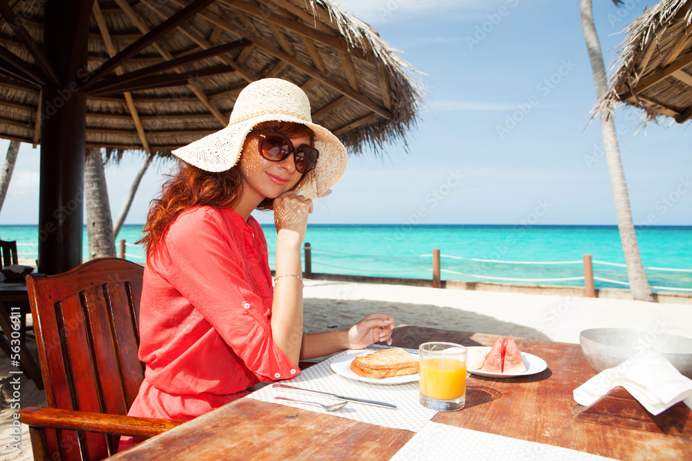 Fashion woman having breakfast on the beach