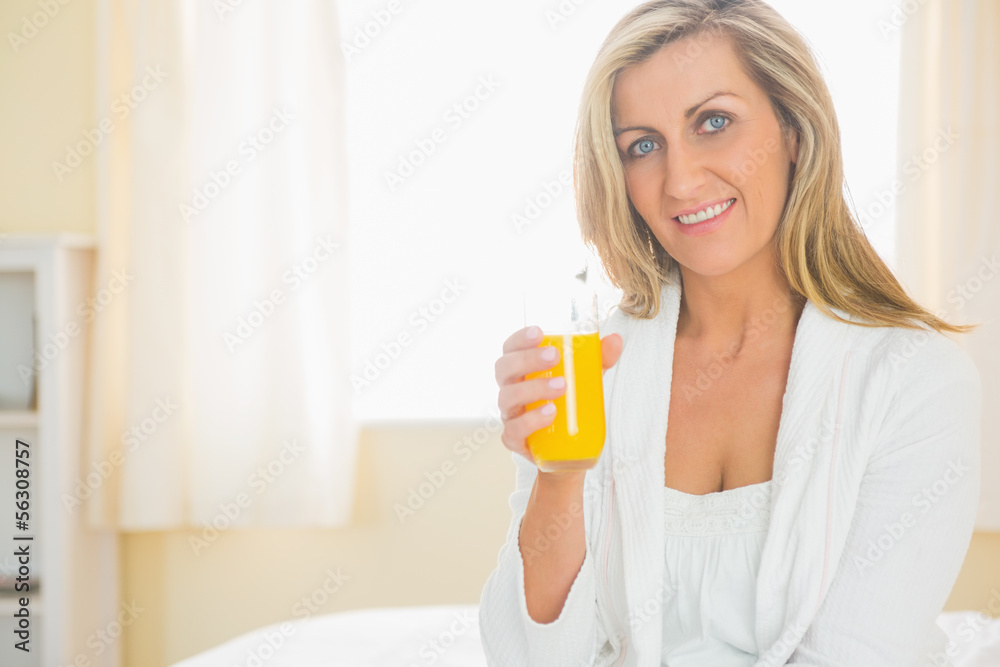 Cheerful woman looking at camera enjoying a glass of orange juic Cheerful woman looking at camera enjoying a glass of orange juic