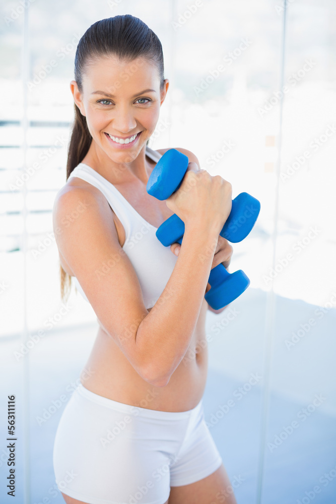 Happy woman exercising with dumbbells smiling at camera Happy woman exercising with dumbbells smiling at camera