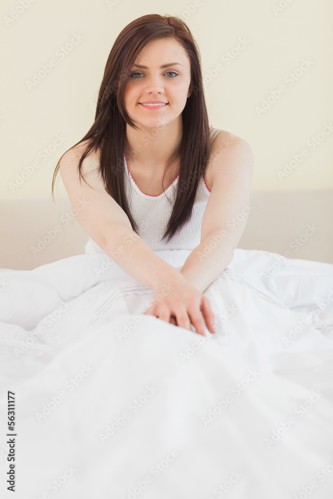 Awakened girl sitting in her bed looking at camera Awakened girl sitting in her bed looking at camera