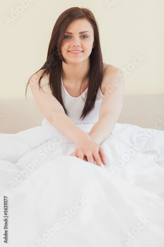 Awakened girl sitting in her bed looking at camera