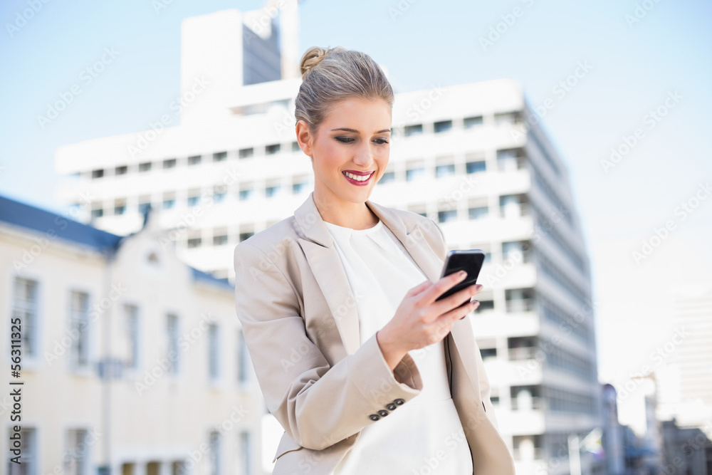 Fototapeta premium Cheerful attractive businesswoman sending a text message