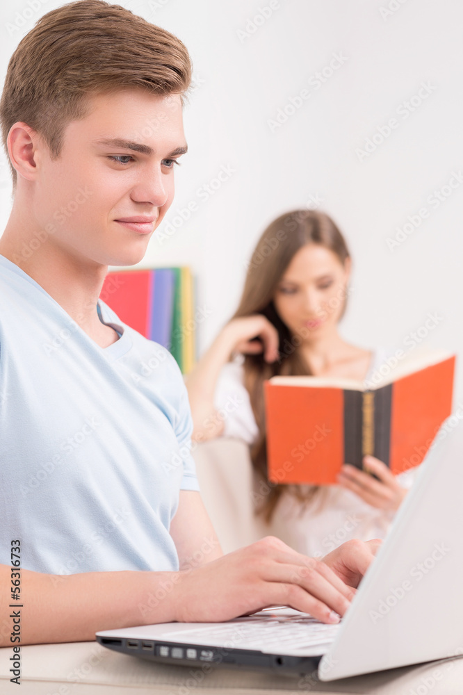 Loving couple at home. Cheerful young man working at the compute Loving couple at home. Cheerful young man working at the compute
