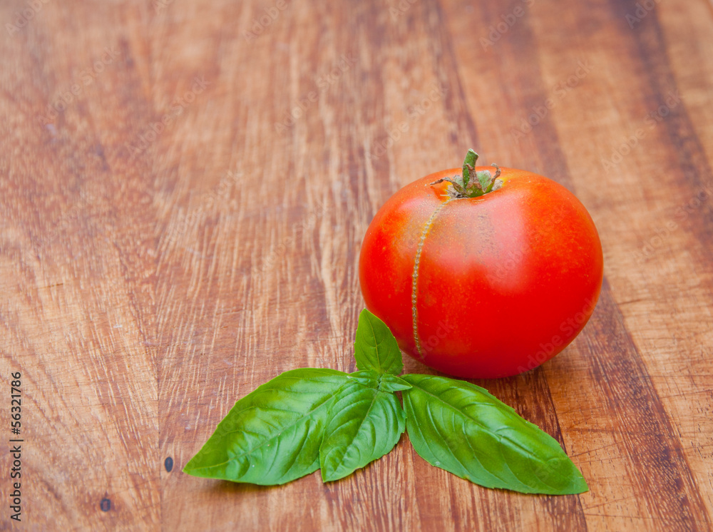 Tomato and basil on rustic, dark wood cutting board Tomato and basil on rustic, dark wood cutting board