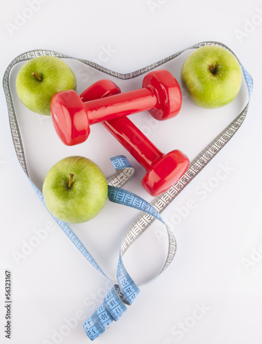 Apple, measurement tape and dumbbell