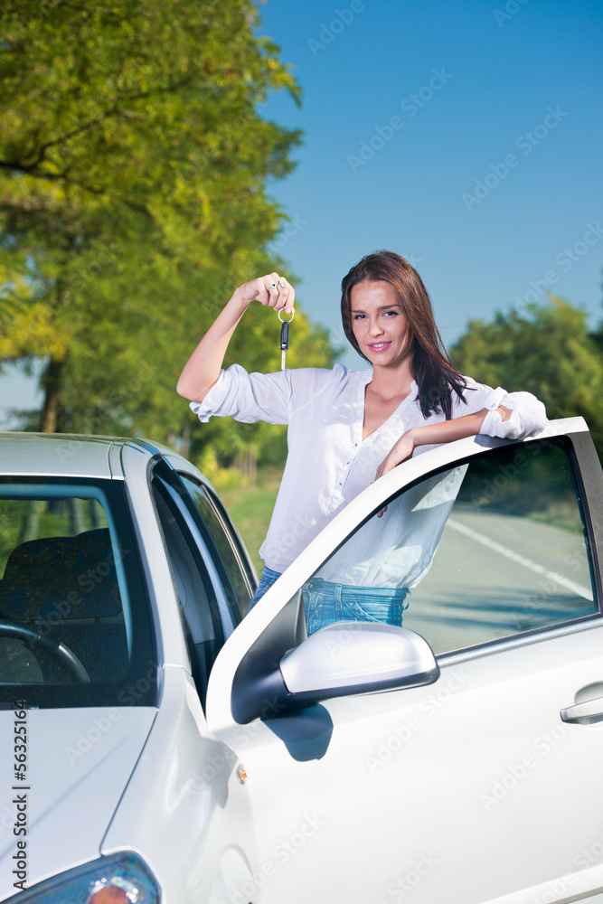 Beautiful woman standing next to a car holding car keys