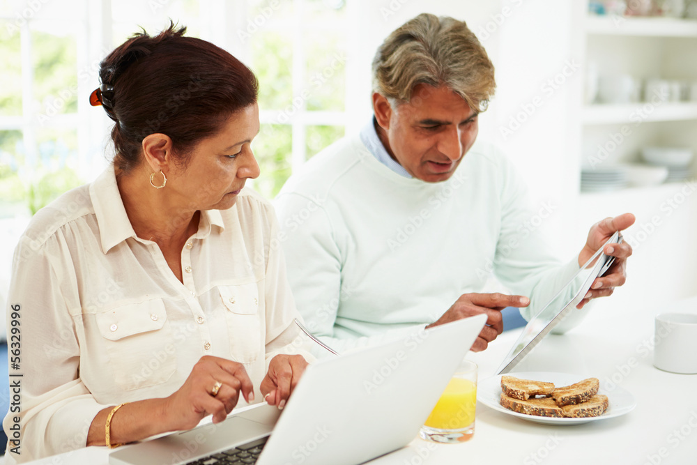 Senior Indian Couple Using Laptop And Digital Tablet At Home Senior Indian Couple Using Laptop And Digital Tablet At Home