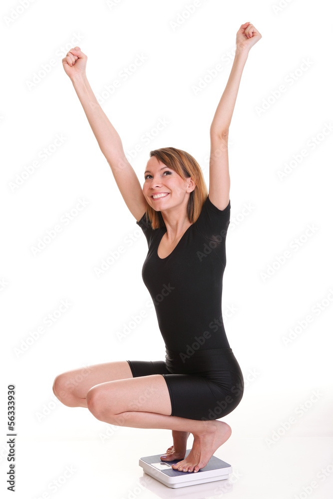 Portrait of a happy woman squatting on scales isolated
