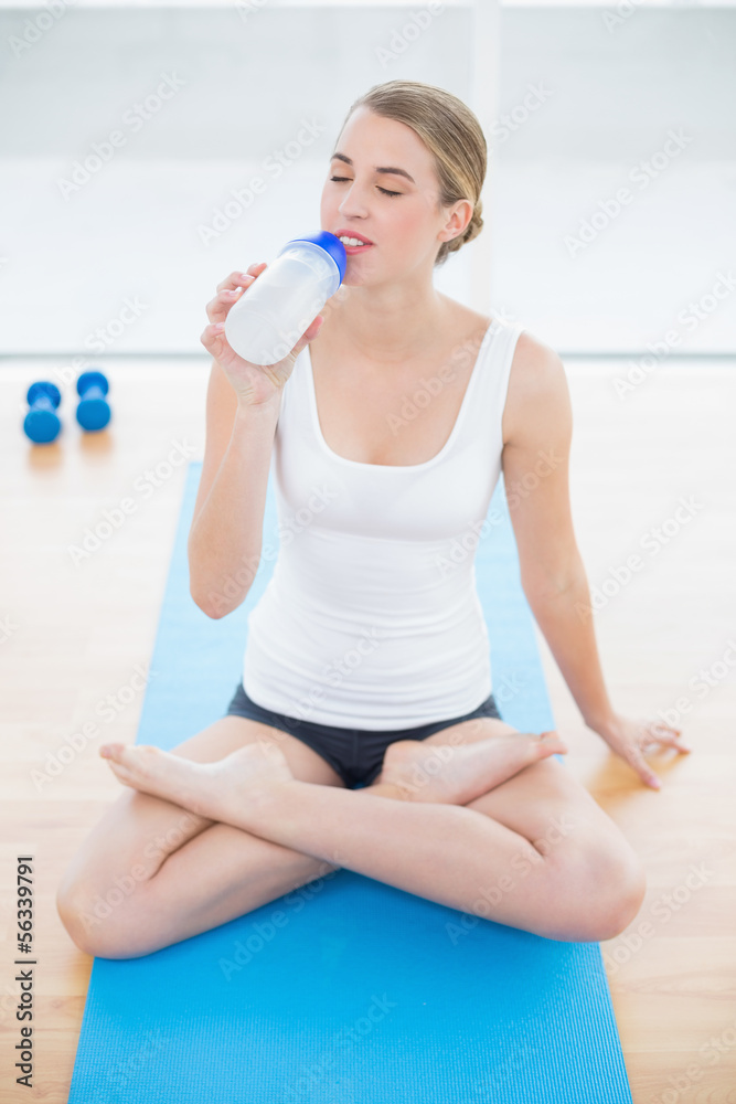 Sporty woman in lotus position drinking water Sporty woman in lotus position drinking water