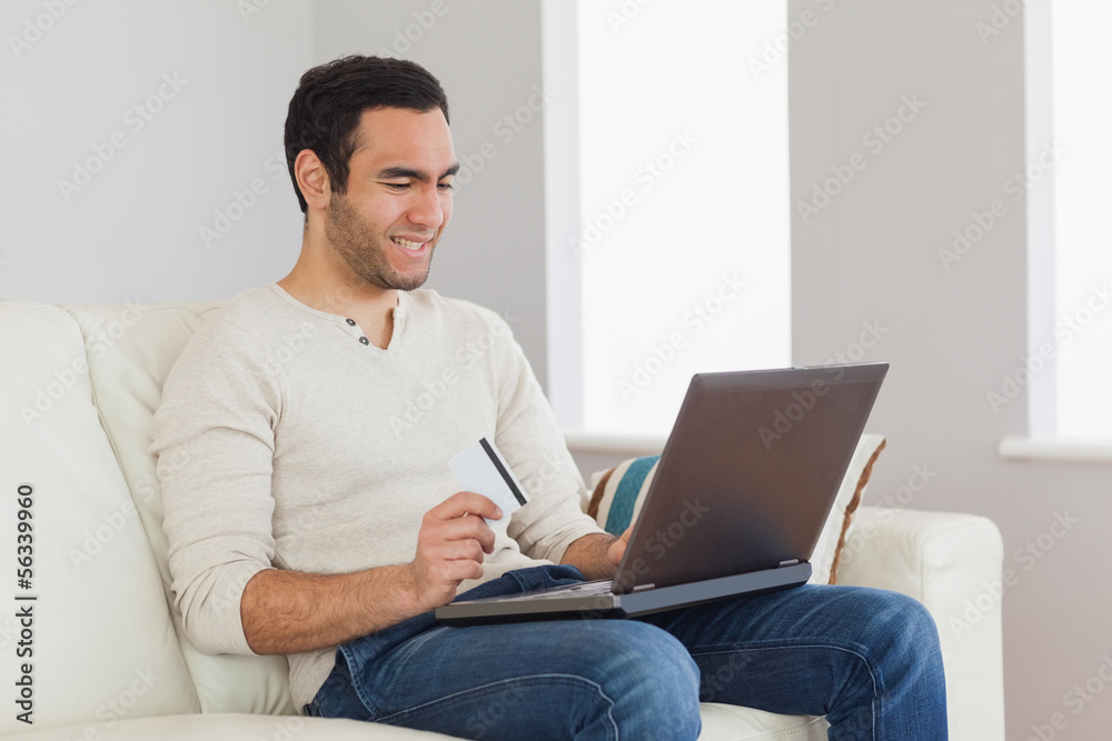 Cheerful handsome man using his credit card to buy online Cheerful handsome man using his credit card to buy online