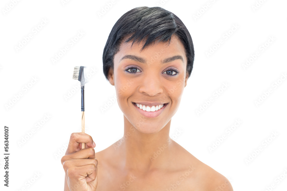 Happy black haired woman holding a brow brush Happy black haired woman holding a brow brush