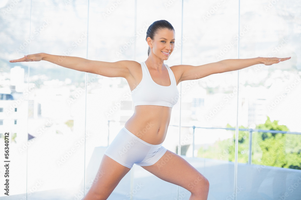 Cheerful fit woman stretching in yoga warrior pose Cheerful fit woman stretching in yoga warrior pose