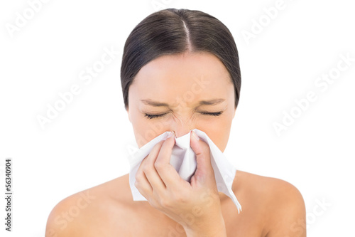 Brunette woman sneezing in a tissue
