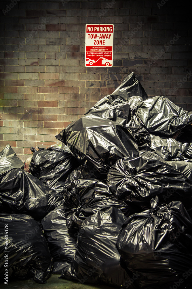 Black trash bags piled up against grungy urban wall
