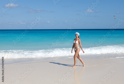 The young woman in the New Year's cap walks on a beach