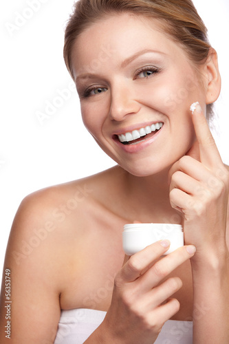 Woman applying cosmetic cream on a clean fresh face
