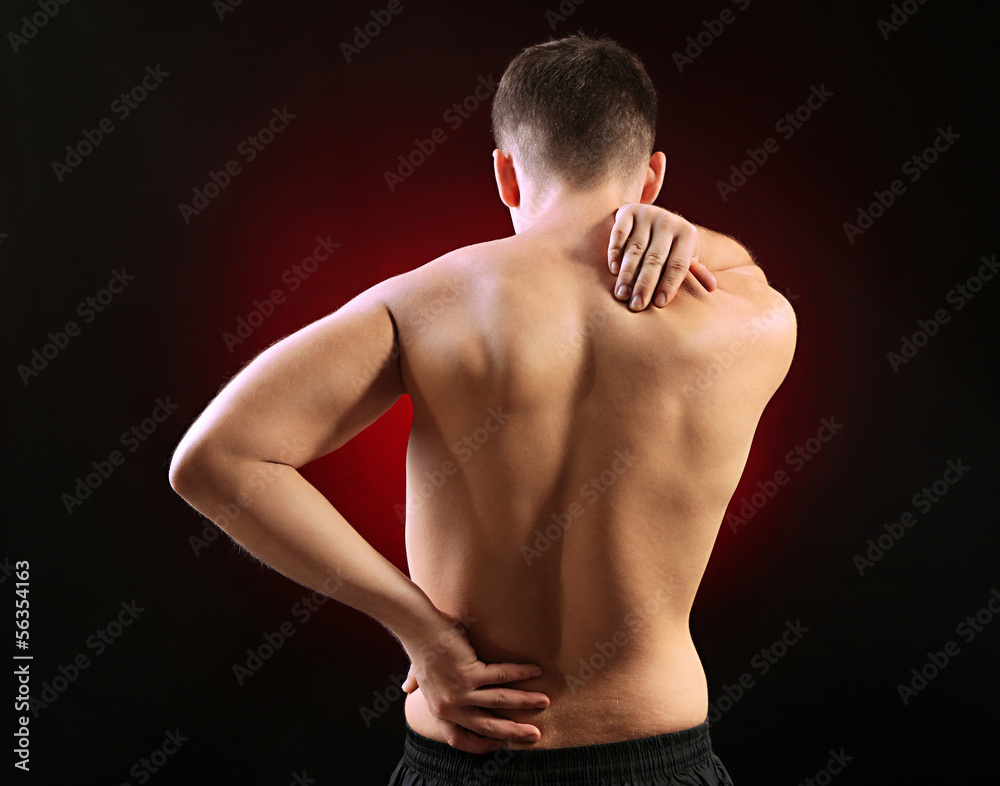 Young man with back pain, on red background