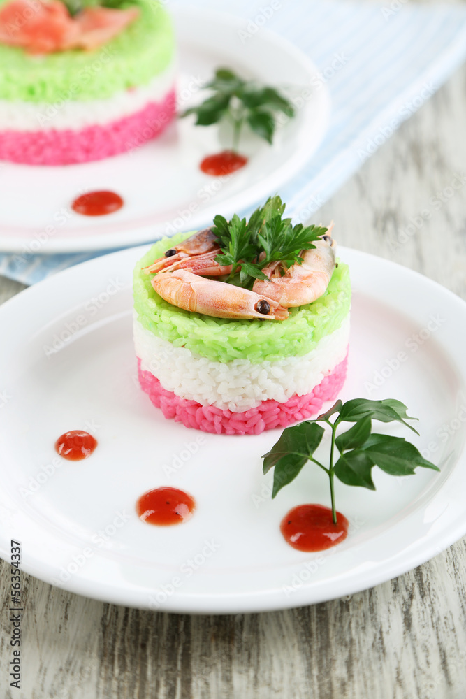 Colored rice on plates on napkin on wooden table Colored rice on plates on napkin on wooden table